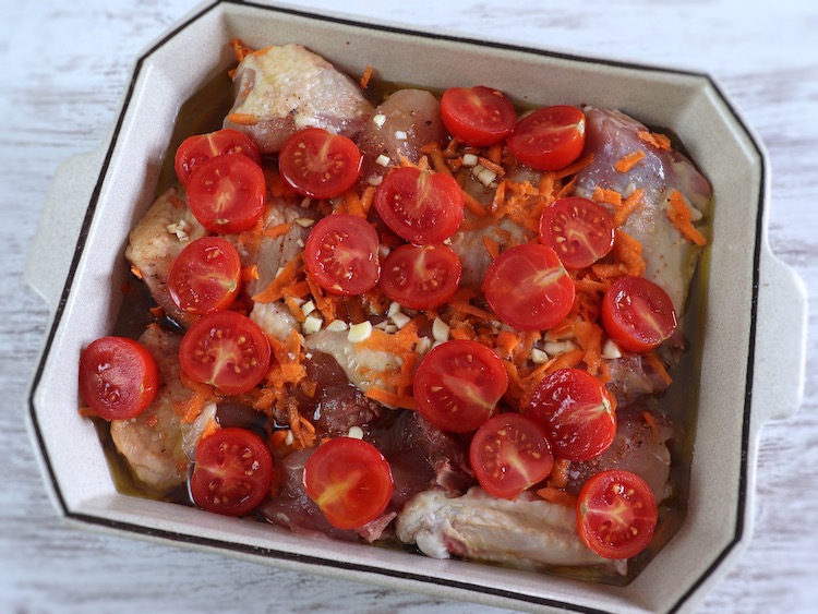 Chicken seasoned with cherry tomato and carrot on a baking dish