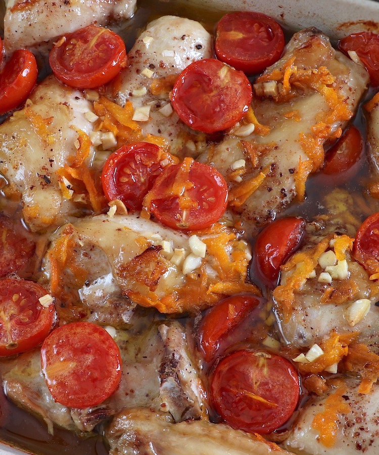 Baked chicken with cherry tomato and carrot on a baking dish