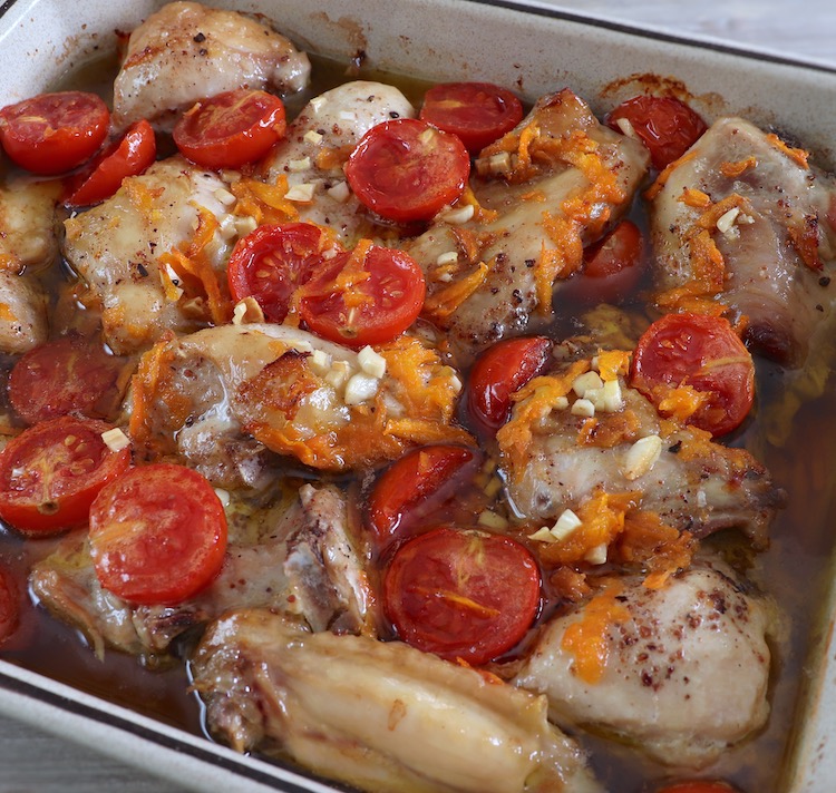 Baked chicken with cherry tomato and carrot on a baking dish
