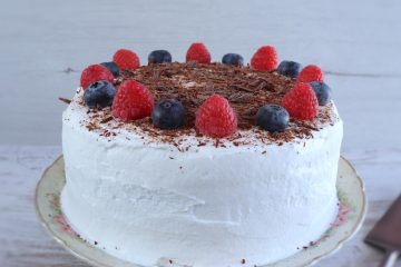 Cocoa cake with whipped cream and berries on a plate