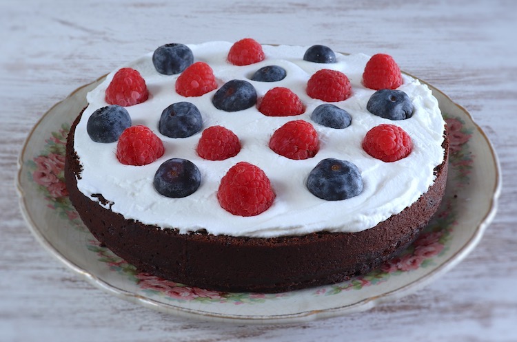 Cocoa cake sliced in half filled with cream and berries
