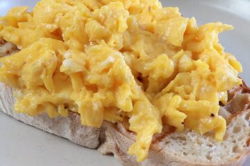 Scrambled eggs over a toasted bread slice on a plate