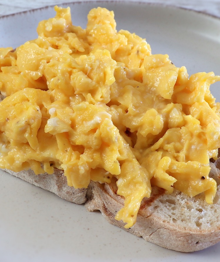 Scrambled eggs over a toasted bread slice on a plate