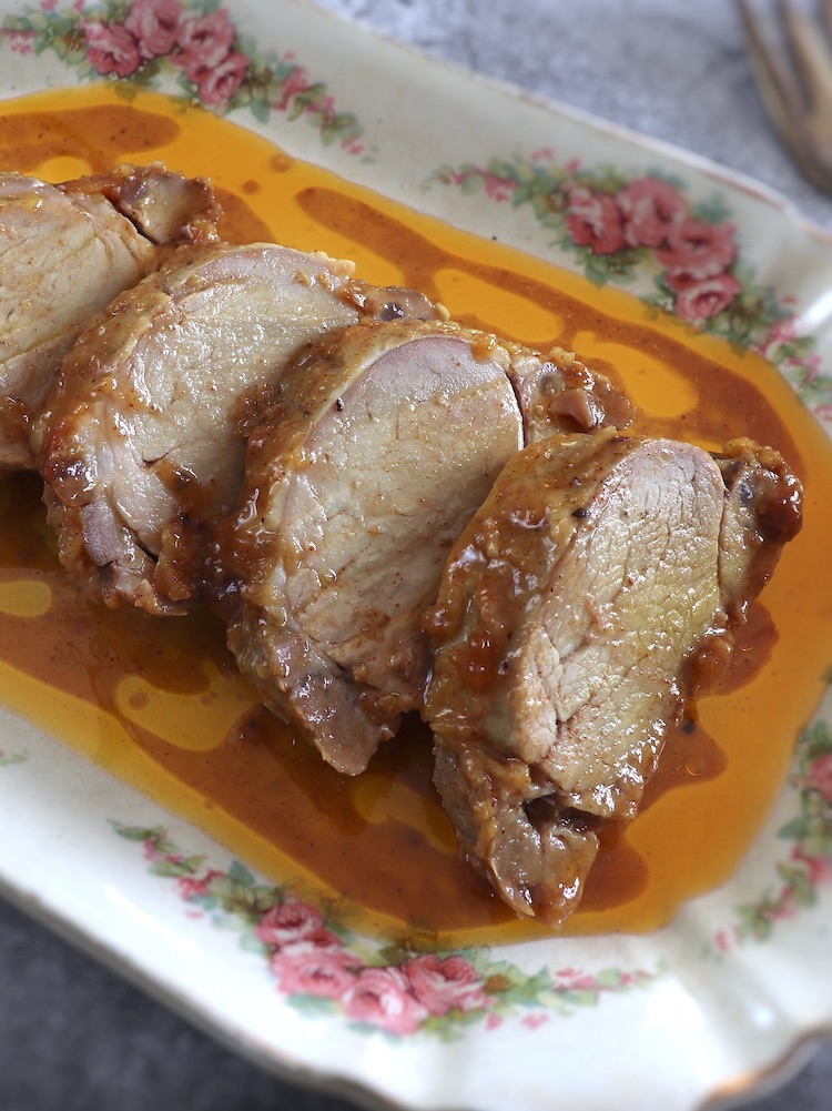 Slices of baked pork tenderloin with honey and mustard on a rectangular platter