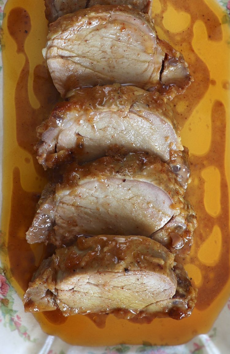 Slices of baked pork tenderloin with honey and mustard on a rectangular platter
