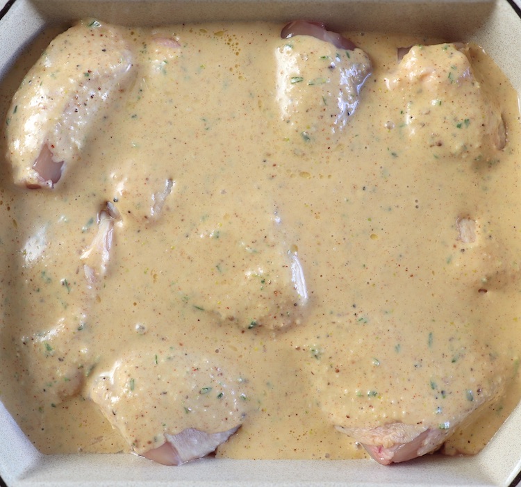 Chicken drizzled with lemon and garlic sauce on a baking dish