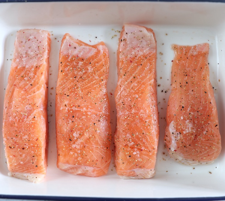 Lombos de salmão temperados com sal e pimenta numa assadeira