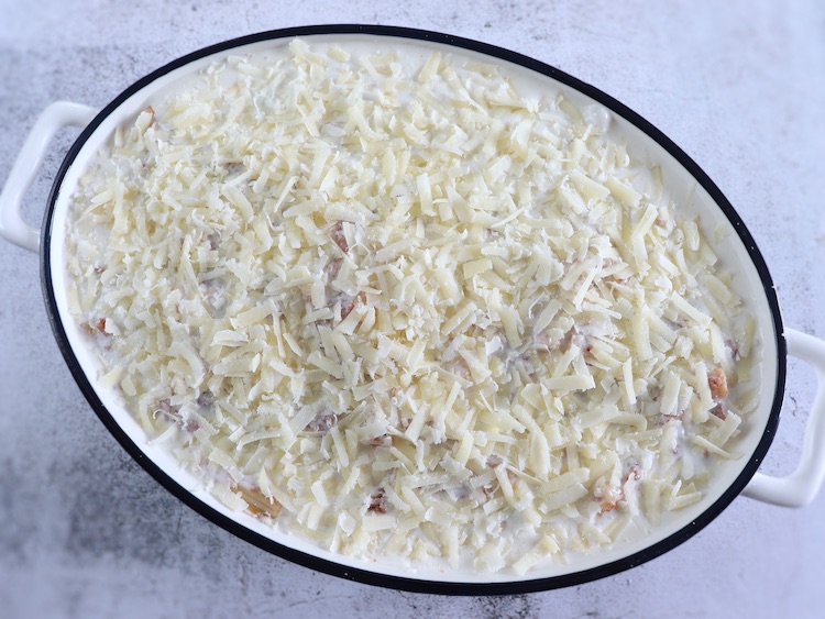Ground meat, penne pasta, béchamel and cream sauce and grated parmesan cheese on a baking dish