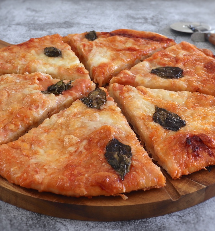 Fatias de pizza Marguerita numa tábua redonda de madeira