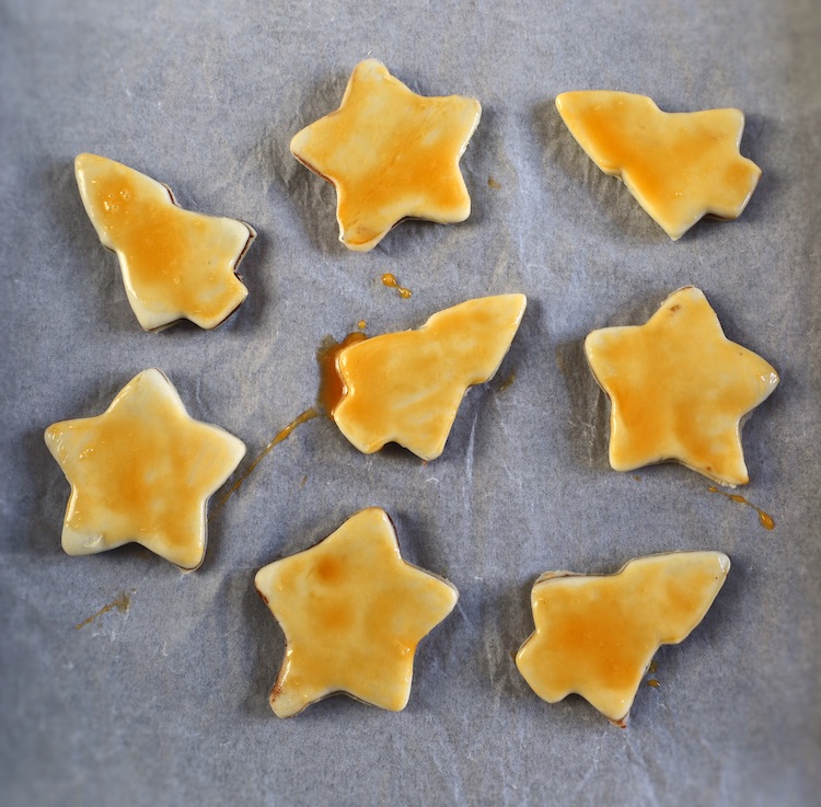 Small stars and trees brushed with egg yolk on a baking tray