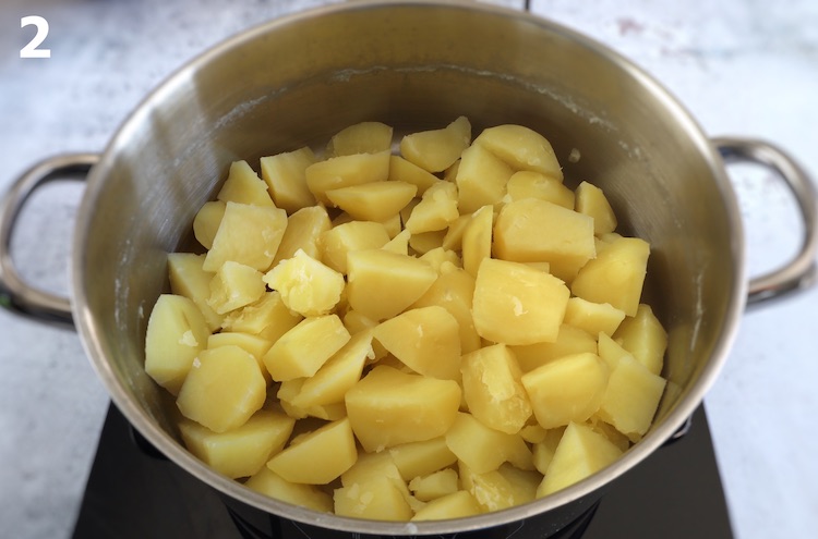 Boiled potatoes cut into small pieces on a large saucepan