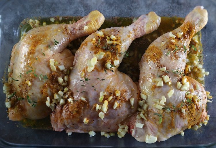 Chicken Leg Quarters seasoned with spices on a glass baking dish