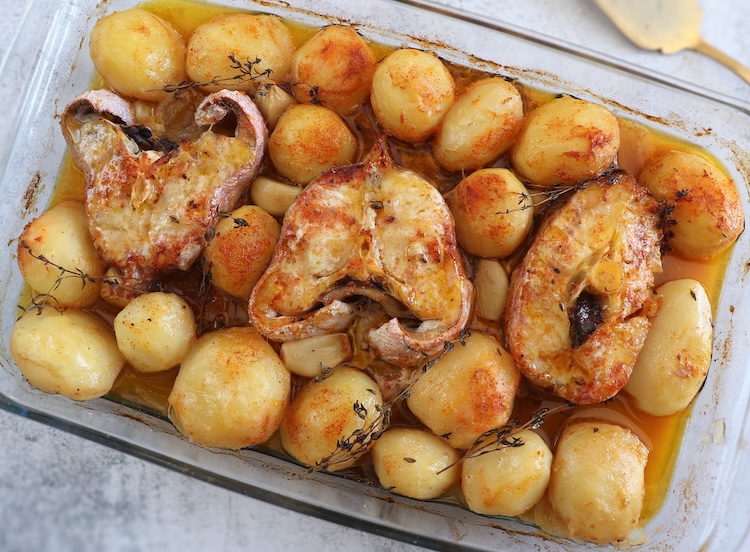 Baked fish with lemon and thyme on a glass baking dish