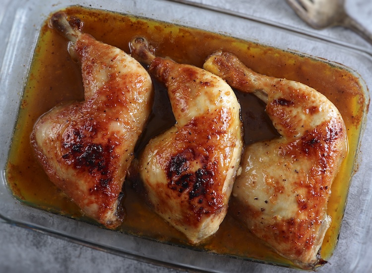 Easy roasted chicken leg quarters with honey on a glass baking dish